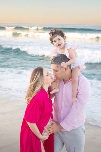 Ensaio de gestante colorido, com mamãe usando vestido rosa ao ar livre.