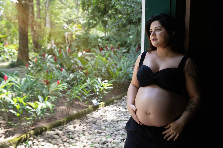Foto da barriga da gestante em detalhe, com luz suave no jardim botânico