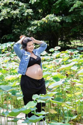 Gestante em ensaio no Jardim Botânico, com folhas verdes ao fundo.