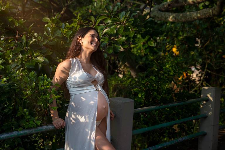 Gestante sorrindo em ensaio com no maio da natureza na Praia Vermelha.