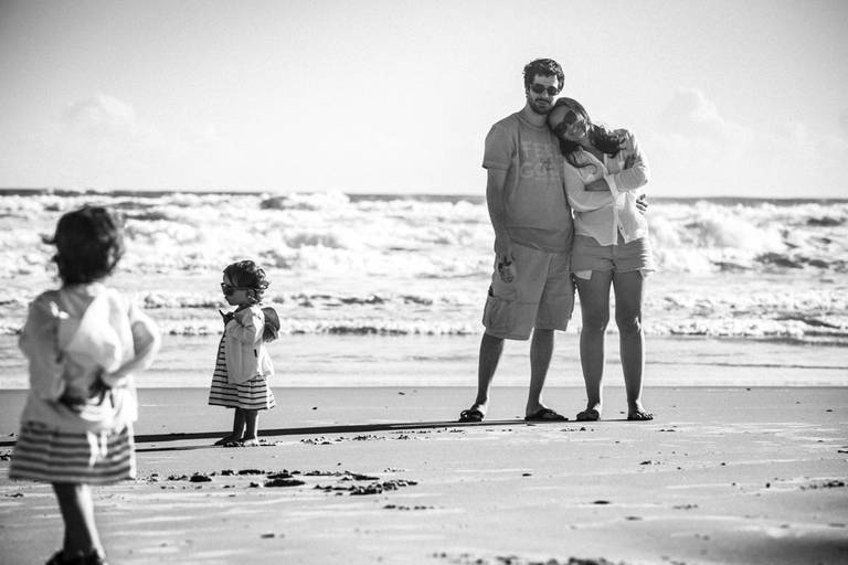 pais observando gêmeas na praia