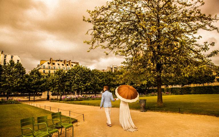 noivos caminhando com guarda chuva no jardim da tulherias no louvre em paris