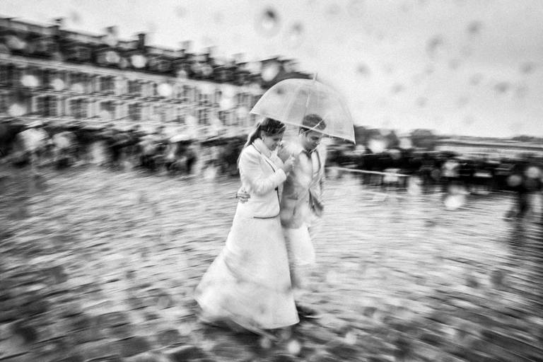 noivos caminhando com guarda chuva no chateau de versailles em paris