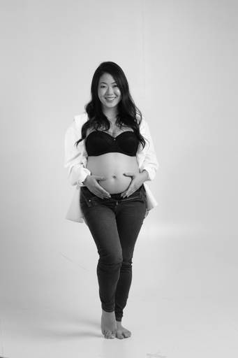 Fotógrafa Alexandra paz direcionando a pose da gestante. Destaque para o coração na barriga em estúdio.