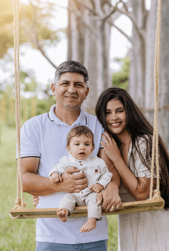 Ensaio externo de bebê com família pose no balanço de madeira pela fotógrafa Alexandra Paz, em Brasília