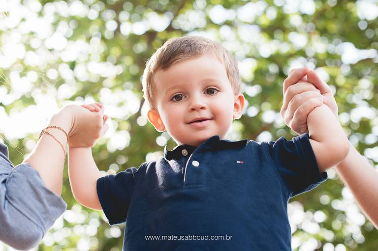 criança sendo suspensa pelos braços pelos pais