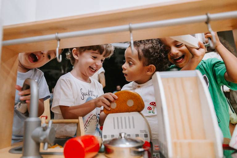 meninos brincam felizes numa cozinha de madeira o vao da cozinha emoldura a foto