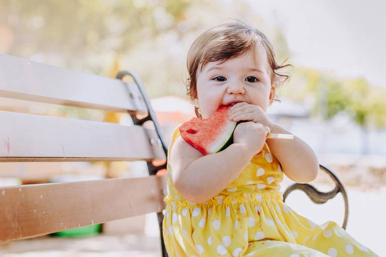 menina de 1 ano se delicia com melancia em seu piquenique