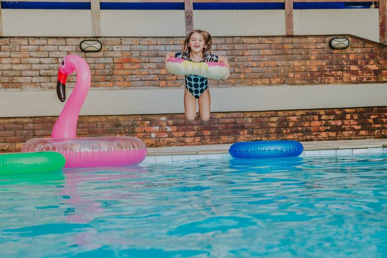 menina saltando de boia na cintura em piscina de condominio no leblon