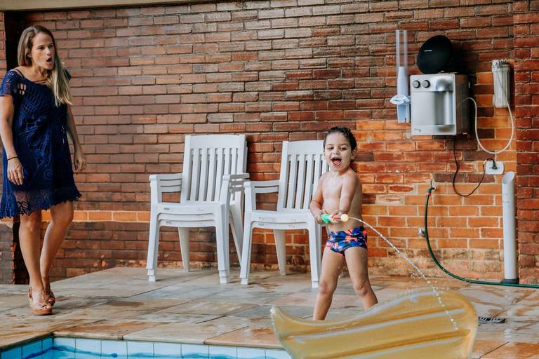 criança brincando de pistola d'agua sendo repreendido por mulher