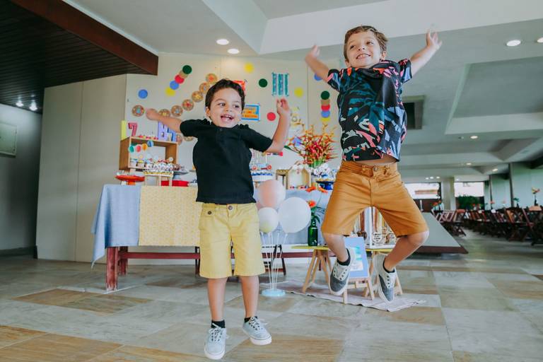 irmaos pulam em frente a mesa do bolo alegremente em festa com tema olimpiadas