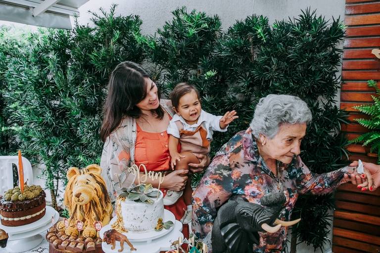 bisavo saindo da mesa do bolo e bisneto no colo da mãe  brincando com ela