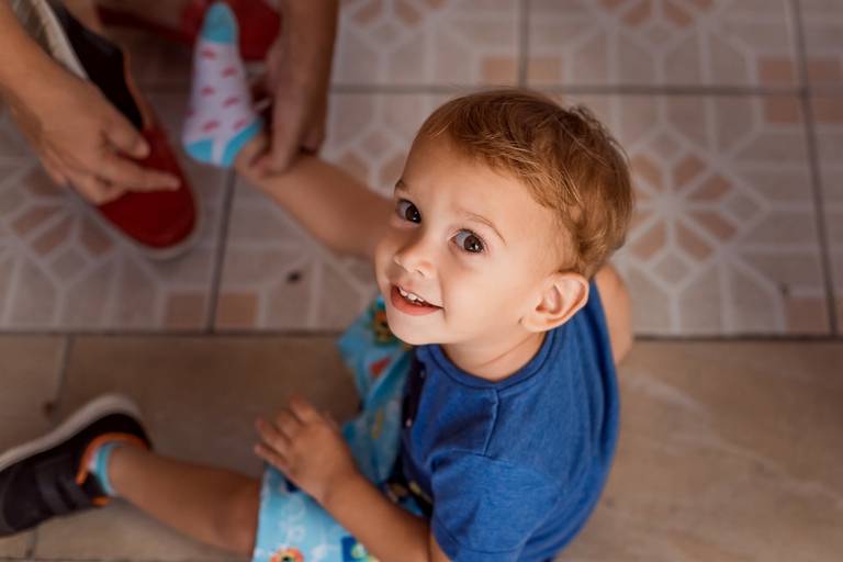 menino com olhar dócil sento no chao olha para a camera de baixo pra cima