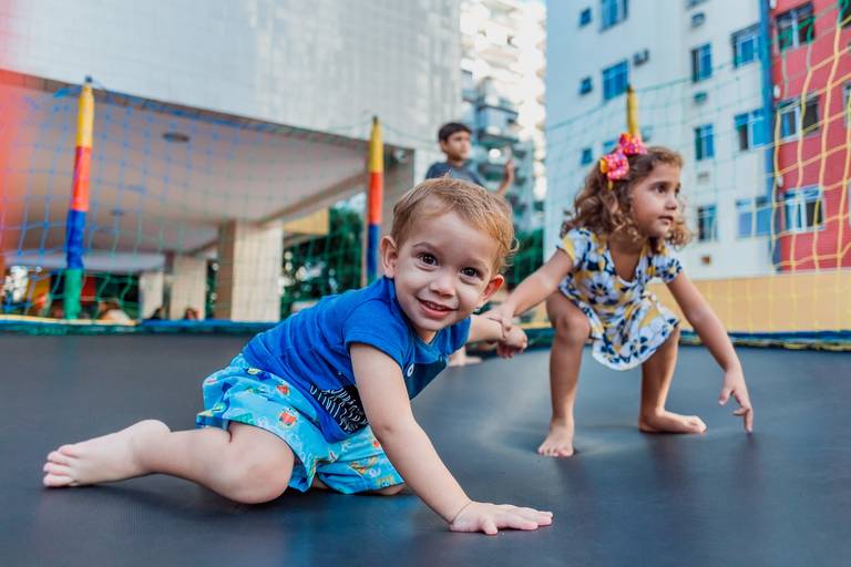 duas crianças no pula pula uma delas o0lha pra camera