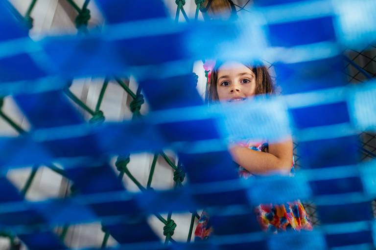 menina olhando por entre a tela do brinquedão