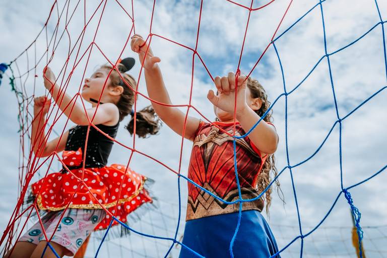 detalhe das mãos de duas meninas se apoiando na rede de pula pula