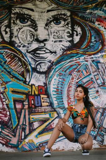 debutande agachada em frente a um painel de grafitte na praça mauá no rj