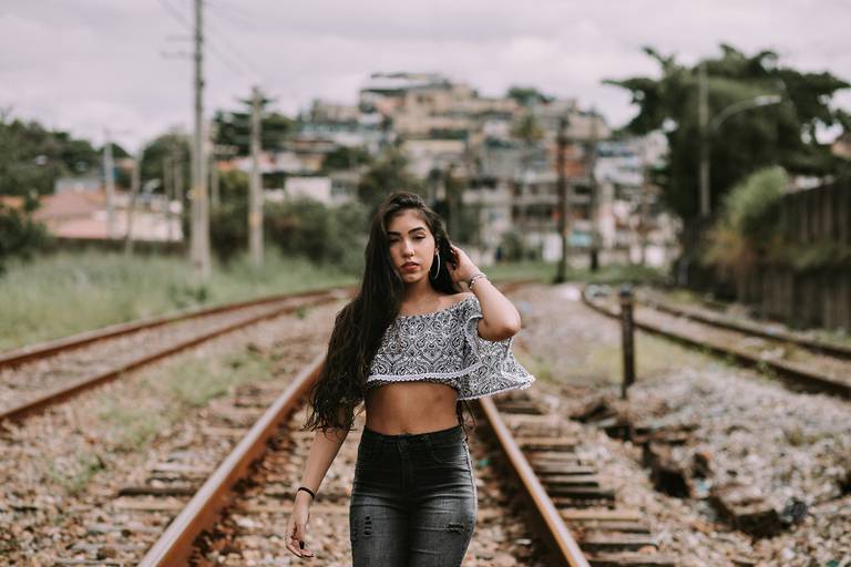 debutante caminhando na linha do trem olhando para a camera e mexendo nos cabelos 