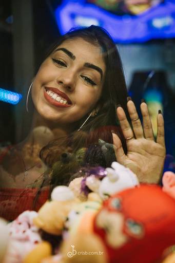 foto de menina debutante sorrindo numa máquina de ursinhos de parque