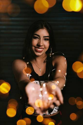 foto de book debutante de menina segurando fio de luz e sorrindo pra camaera com os braços estendidos em direçãoà camera