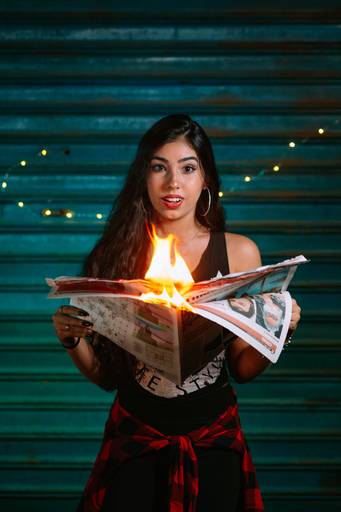 foto de menina segurando jornal queimando e fazendo cara de surpesa
