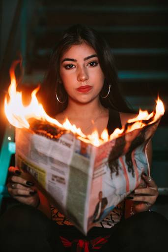 foto de menina debutante segurando um jornal que pega fogo