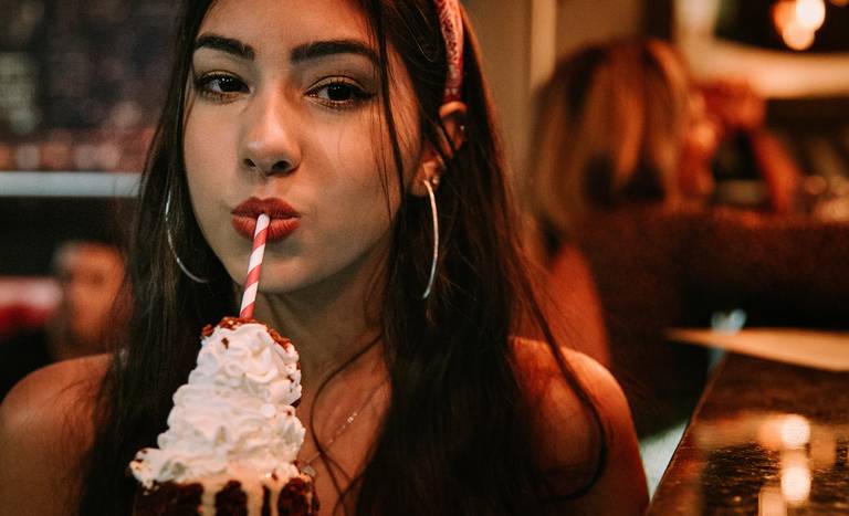 foto de close de debutante tomando um milkshake de canudo vermelho e branco