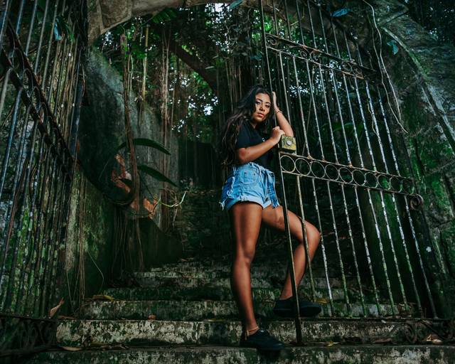 book de debutante em mão no largo do boticario ela esta encostada num portão grande, foto em plngee