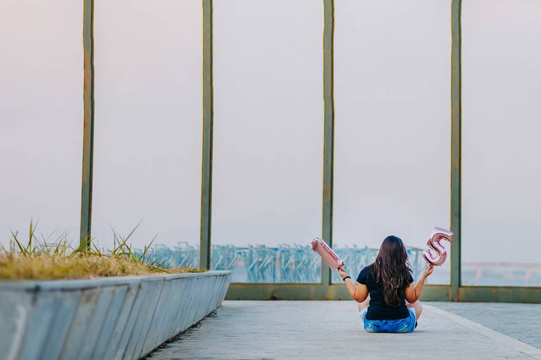 foto de debutante de costas para a camera segurando baloes com o numero quinze na praça mauá