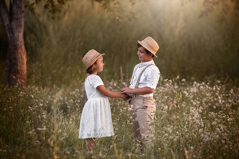 Hermanos tomados de la mano en el campo. Foto cándida, vestidos de blanco. Sesión para el book en Santa Fe. Barby Massei