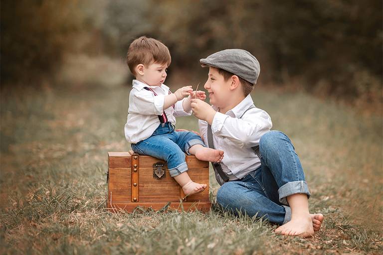 Hermanos en el campo jugando y disfrutando de su book de fotos. Ambos con jeans azul y camisa blanca, disfrutando la naturaleza en el campo, fotos en Santa Fe. Fotografía Barby Massei.