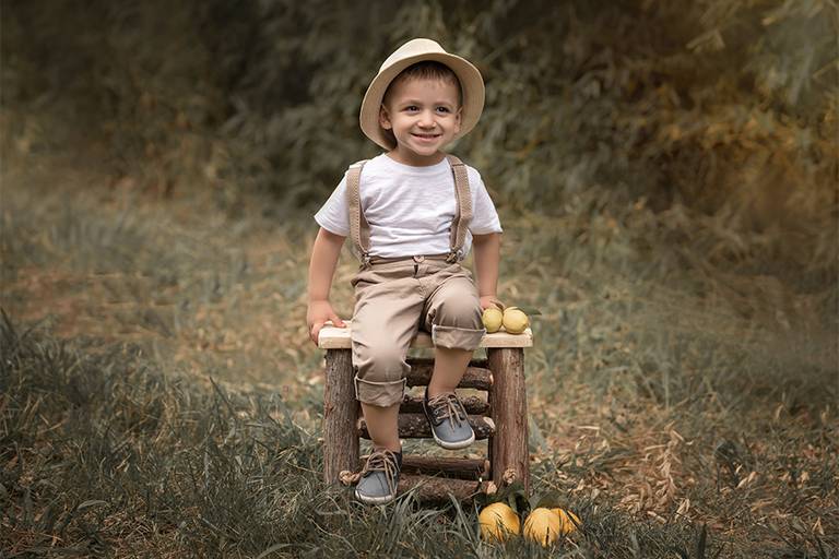 Niña en el bosque, sentado en su escalerita de madera, con sus limones amarillos. Book de fotos al aire libre, Barby Massei fotógrafa. Sesión niños en Santa Fe. Book infantil.
