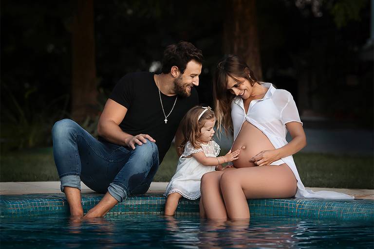 Familia disfrutando al aire libre, una bello día de verano. Mamá, papá y su hermanita. Ellas con sus vestidos blancos y el papá con su jeans y remera negra. Caricias, mimos, y mucha alegría. Barby Massei fotógrafa. Sesión familiar. Maternidad en Santa Fe
