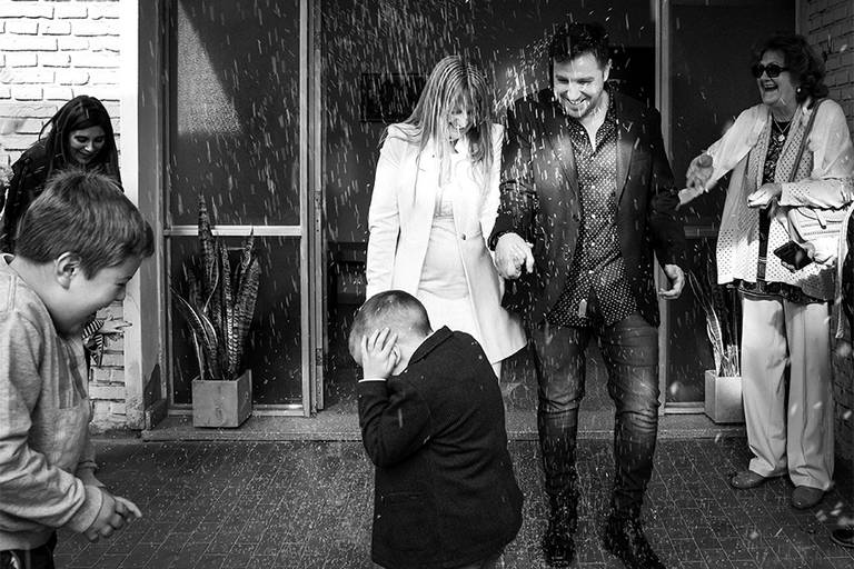Niño en medio del arroz a la salida del casamiento de sus papas. Festejos por el matrimonio de la ceremonia civil en Santa Fe. Barby Massei foto blanco y negro. San José de la Esquina.
