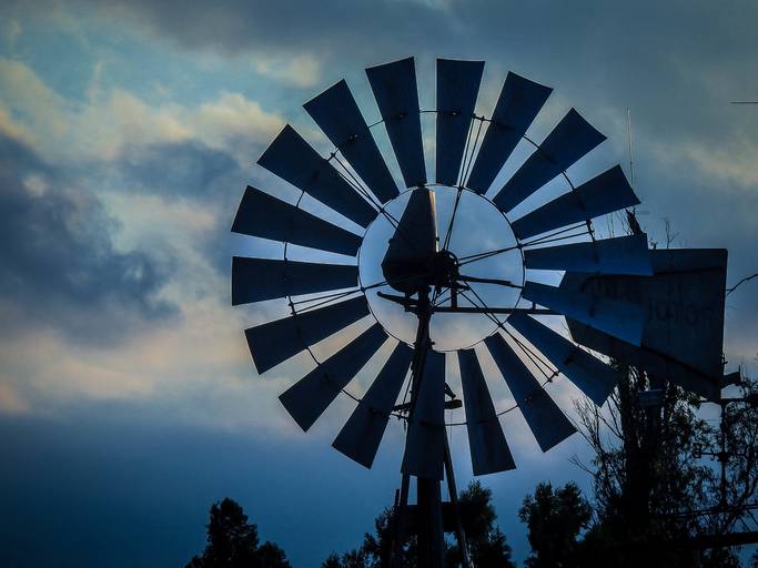 una tardecer en el campo, el cielo oscuro y el molino de viento en primer plano