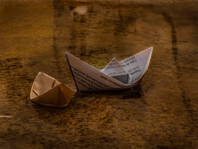 barquitos de papel en charco de agua color dorado
