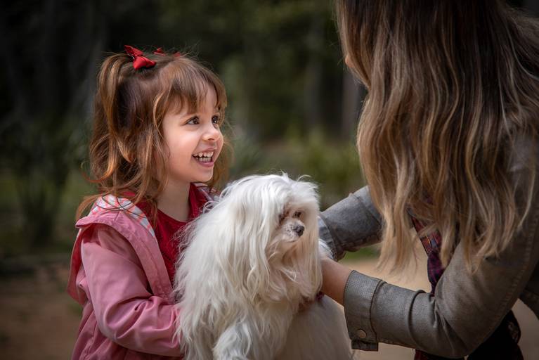 Filha sorrindo ao receber um cachorrinho da mãe