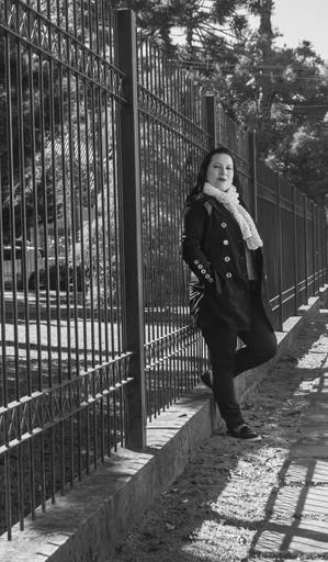 Fotografia preto e branco modelo encostada nas grades olhando para câmera do fotógrafo Tiago Costa Fotografia