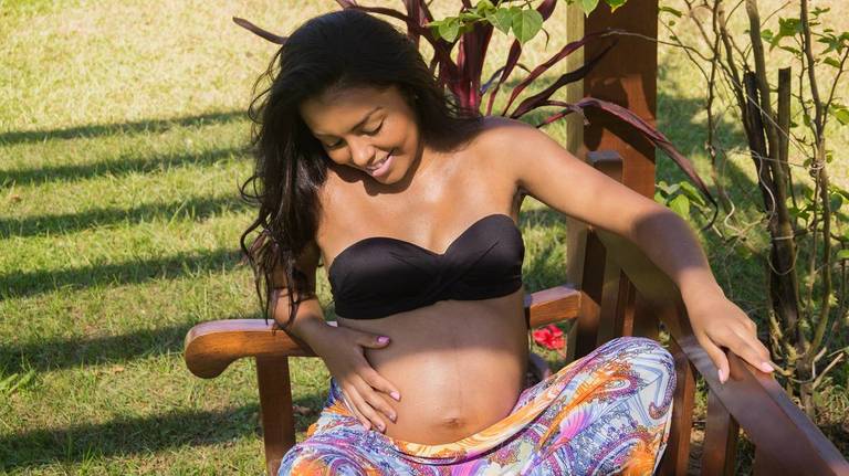 A gestante acaricia sua barriga com olhar de amor, foto de Tiago Costa Fotografia 