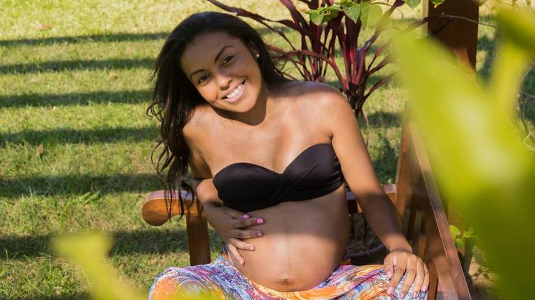 Sentada em um banco a gestante esta sorridente, foto de Tiago Costa Fotografia 