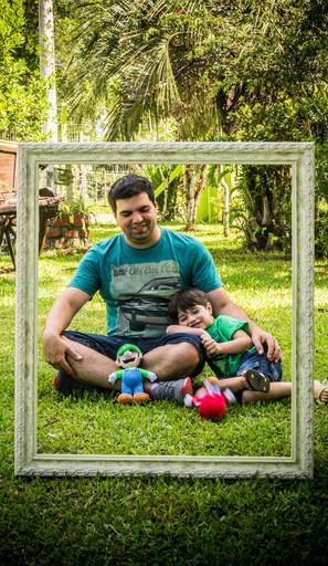 Foto do pai e filho sentados na grama, muito amor envolvido. Tiago Costa Fotografia