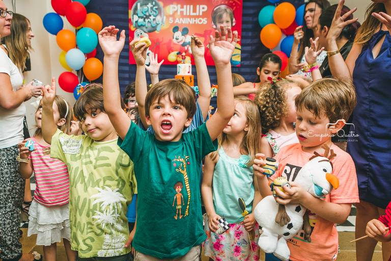 fotografia aniversário crianças brincando com as mãos para o alto na mesa do bolo decoração tema dj