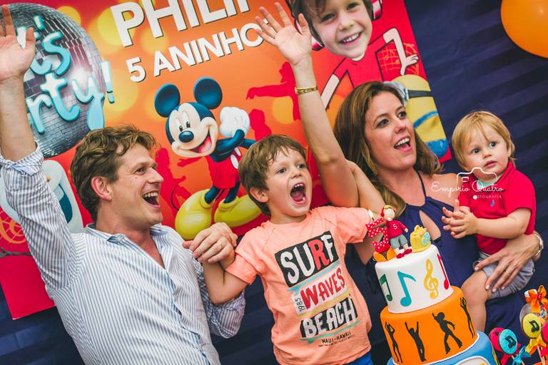 fotografia aniversário aniversariante e família com as mãos para o alto na mesa do bolo decoração tema dj