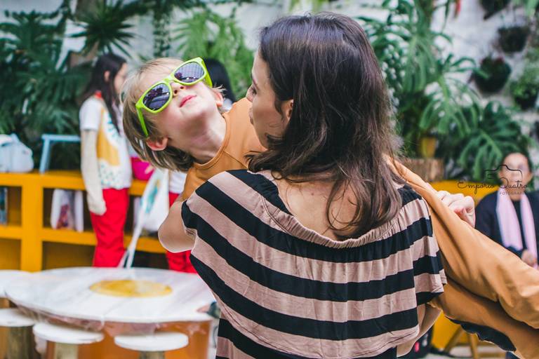 fotografia aniversário criança de óculos de sol brincando no colo de mulher