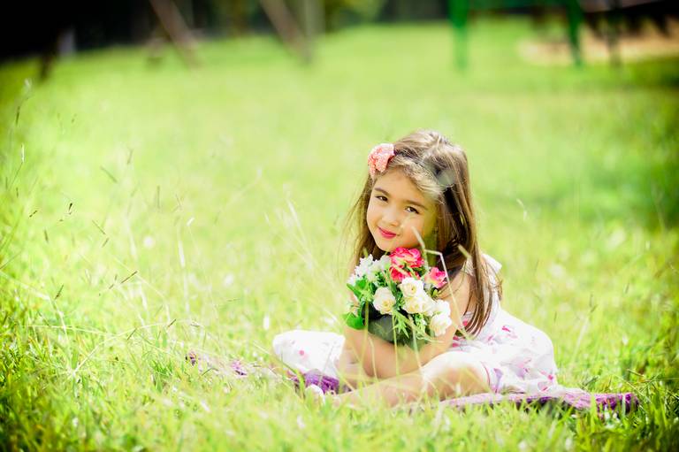 menina sentada na grama em ensaio