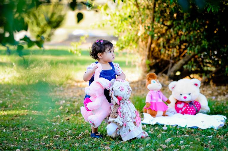 menina andando em gramado com boneca na mao