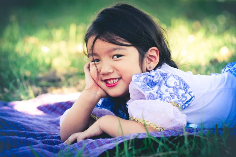 menina oriental deitada na grama