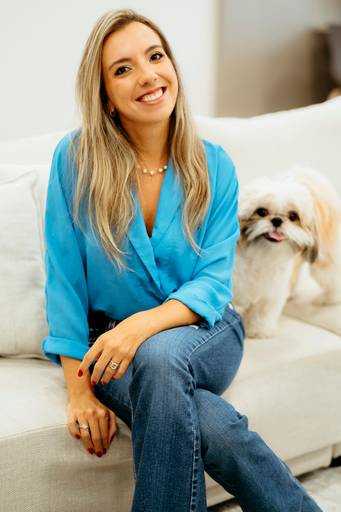Ensaio Corporativo, profissinal. Mulher sentada em sofa olhando para a camera com o cachorro do lado