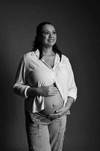 Ensaio gestante em estúdio, gestante esta com a mão na barriga aparecendo, foto em preto e branco