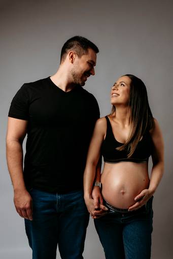 Ensaio gestante em estúdio, barriga está aparecendo, casal se olha e gestante esta usando conjunto da Calvin Klein